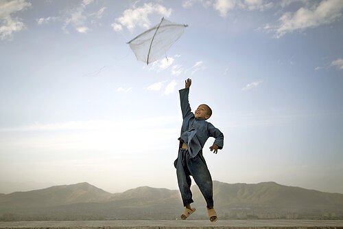 An Afghan boy flies his kite on a hill overlooking Kabul, Afghanistan...